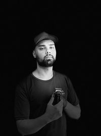 Portrait of young man standing against black background