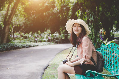 Portrait of woman sitting on bench at park