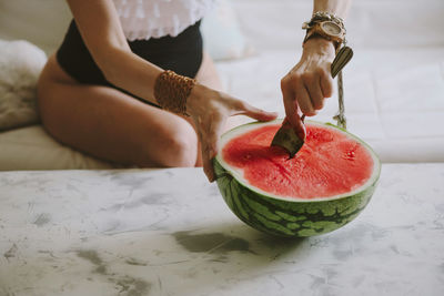 Midsection of woman having watermelon at home