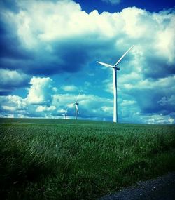 Wind turbines on field against cloudy sky