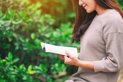 Midsection of woman holding paper outdoors