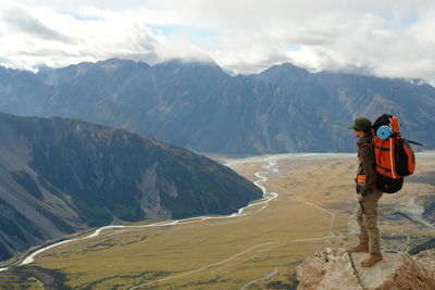 Rear view of man standing on mountain against sky