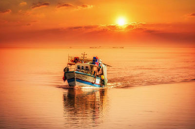 Boat in sea against sky during sunset