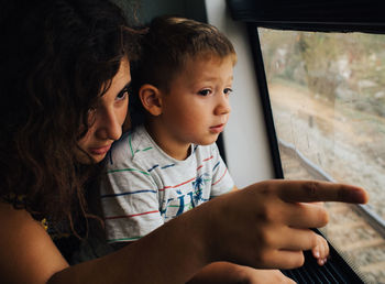 Girl with her little brother looking through the train window