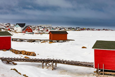 Built structure on snow covered land by sea against sky