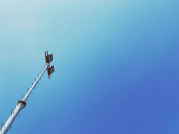 Low angle view of crane against clear blue sky