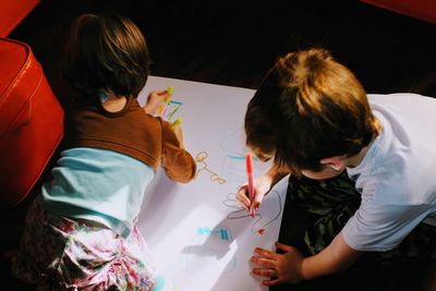 High angle view of kids drawing on paper at home