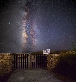 Information sign on field against sky at night