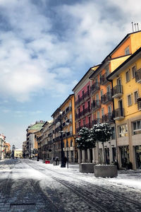 Street by buildings in city against sky