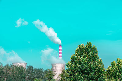 Smoke emitting from factory against blue sky