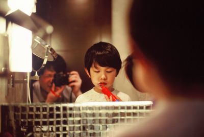 Father photographing while son brushing teeth in bathroom