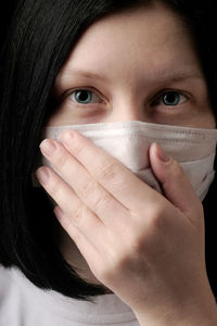 Close-up portrait of woman covering face with hand