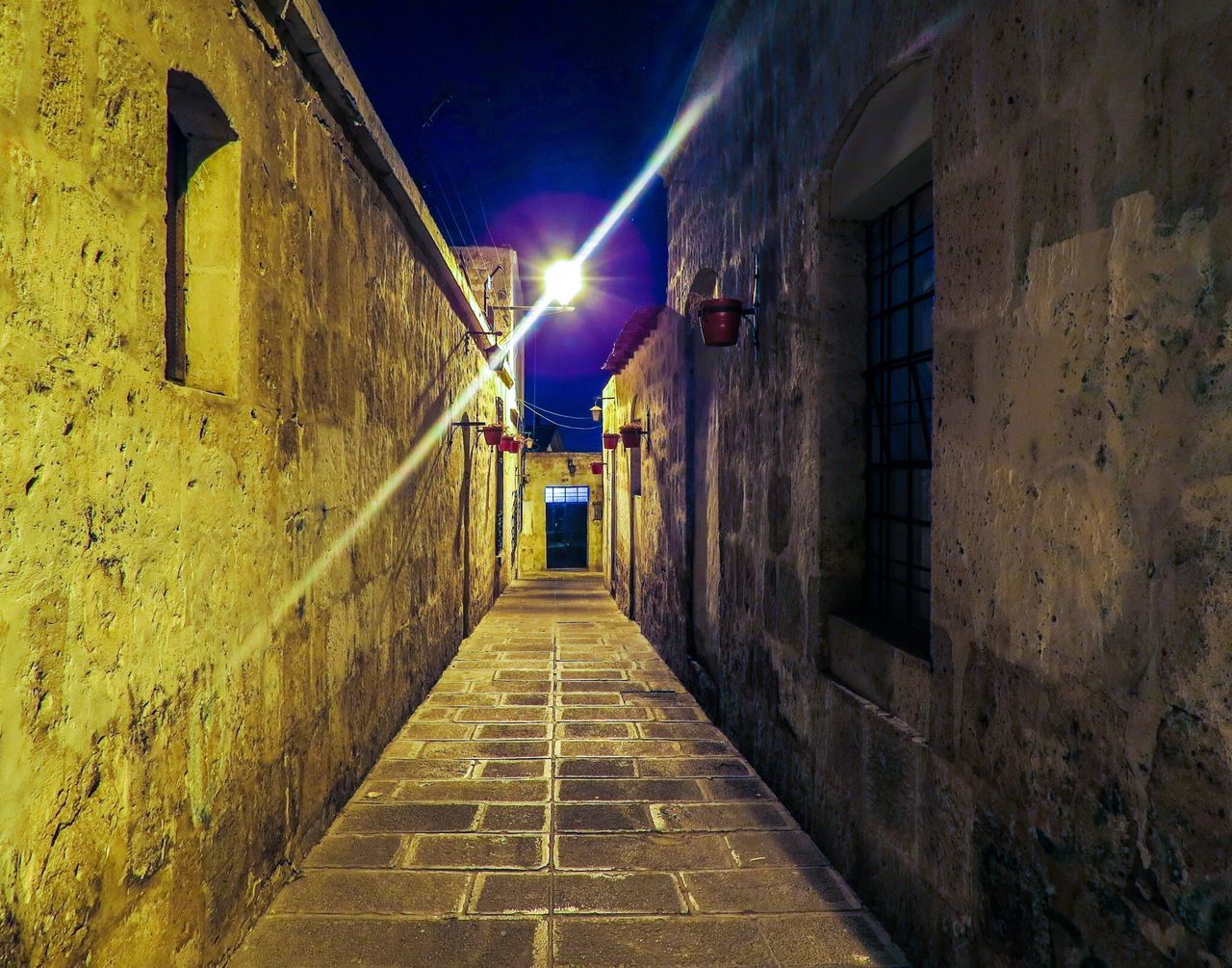 architecture, built structure, building exterior, the way forward, illuminated, night, building, alley, narrow, diminishing perspective, street light, street, residential structure, lighting equipment, residential building, wall - building feature, vanishing point, cobblestone, house, brick wall