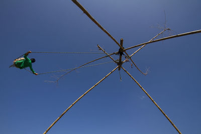 Low angle view of child on bamboo swing