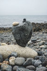 Stones on rocks at beach against sky