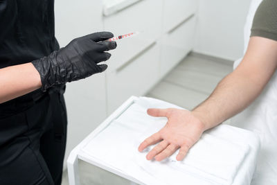 Close-up of man holding hands while sitting on table