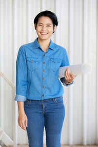 Smiling man holding smart phone while standing on laptop