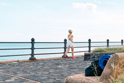 Young attractive sportive woman running on seaside promenade. workout outdoors by the sea.