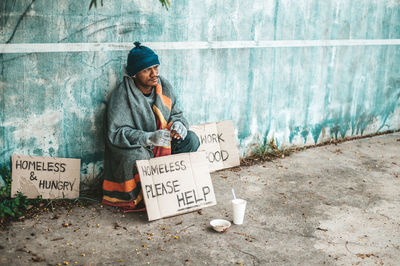 Man sitting by wall with text