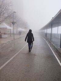 Rear view of man walking on road amidst buildings