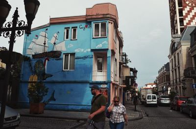 People on street against buildings in city