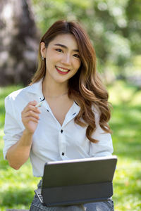 Portrait of young woman using laptop in park