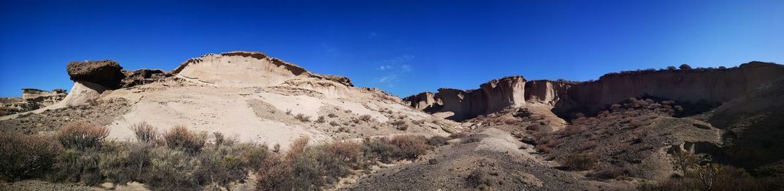 Low angle view of rocky mountains against clear blue sky