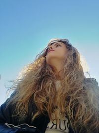 Low angle view of woman with long hair against clear sky