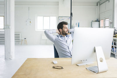 Smiling businessman sitting at desk in office having a break