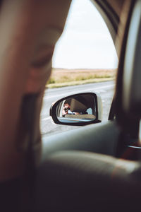 Reflection of man photographing in car