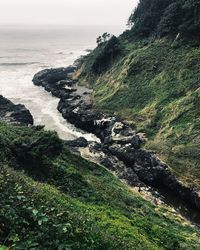 Scenic view of sea by cliff against sky