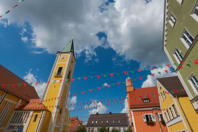 Low angle view of flags hanging amidst buildings against sky