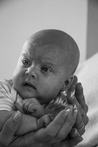 Cropped hand holding baby boy at home