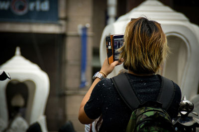 Rear view of man photographing using smartphone