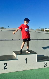 Full length of boy running against clear blue sky