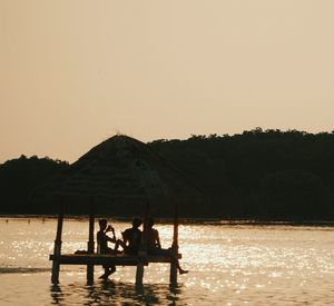 Silhouette people on boat against clear sky during sunset