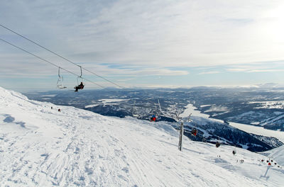 Ski lift over snow covered mountains against sky