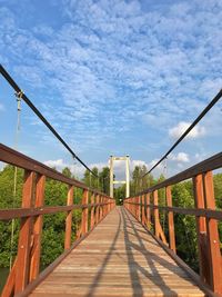 Footbridge over fence against sky