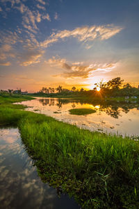 Scenic view of grassy field against sky during sunset