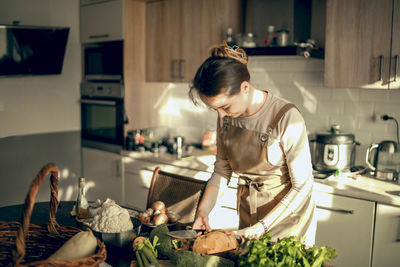 Shoot of athletic woman cutting pumpkin with a knife to prepare in the kitchen at home