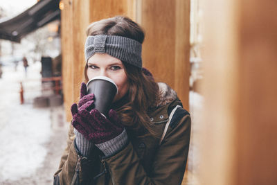 Portrait of young woman drinking coffee outdoors