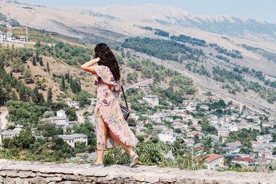 Woman on wall against mountain landscape