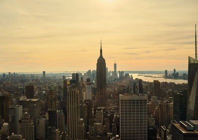 Modern buildings in city against sky during sunset