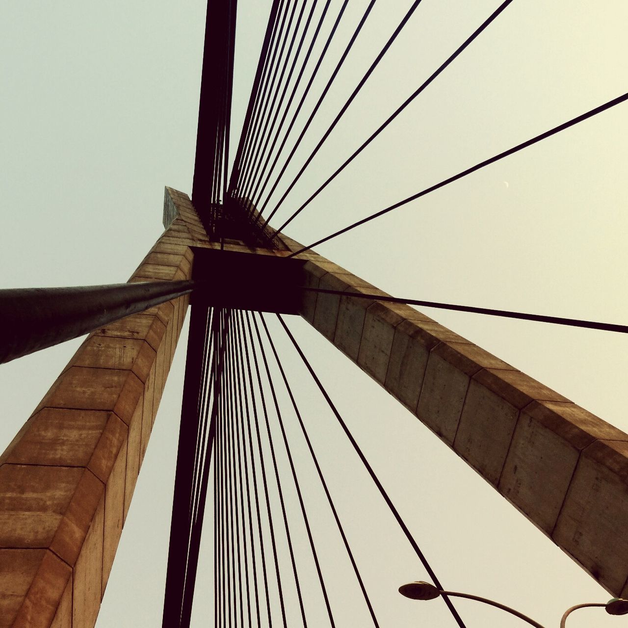 low angle view, built structure, architecture, connection, suspension bridge, bridge - man made structure, engineering, clear sky, cable, tall - high, bridge, cable-stayed bridge, building exterior, international landmark, sky, travel destinations, famous place, steel cable, tower, modern