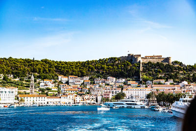 Sailboats in sea against buildings in city