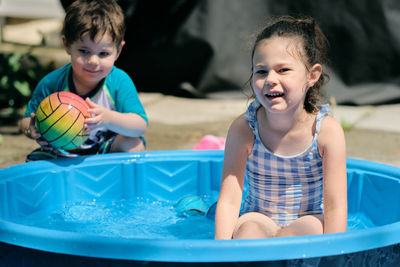 Siblings playing near a water basin in the back yard