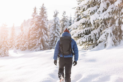 Rear view of man walking on snow covered mountain