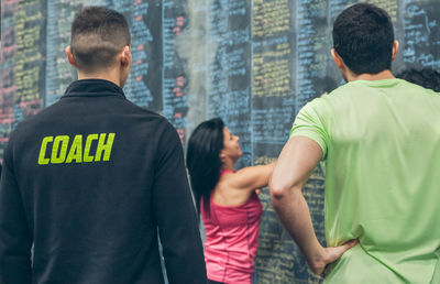 Trainer supervising female athlete writing down results on the gym blackboard