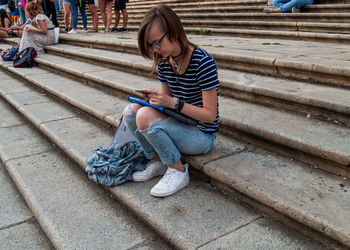 Side view of teenage girl using mobile phone while sitting on steps