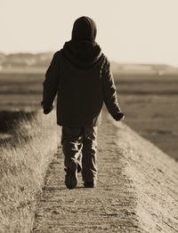 Full length rear view of boy walking on groyne